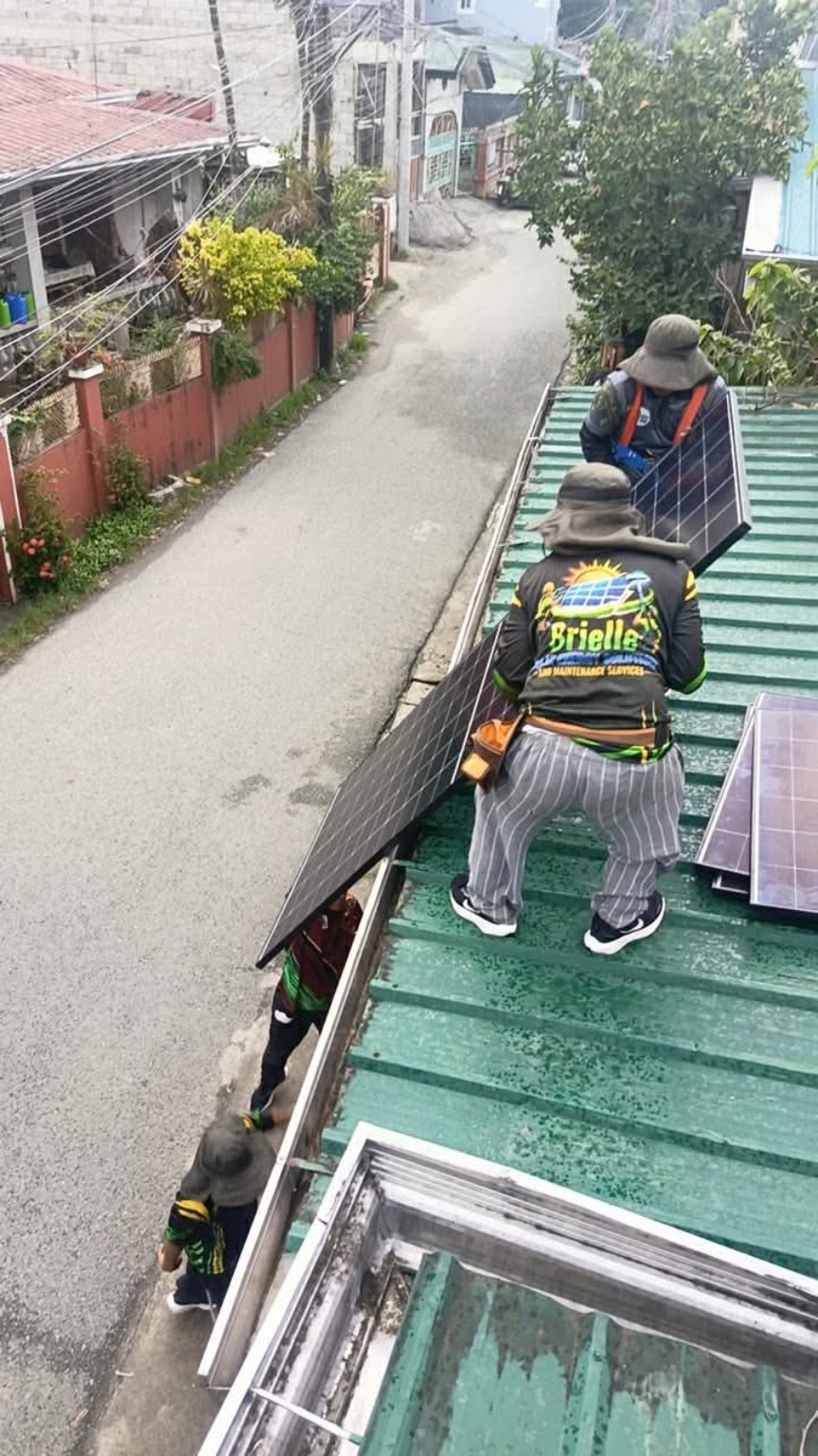 Installer carrying a solar panel beside a residential roof